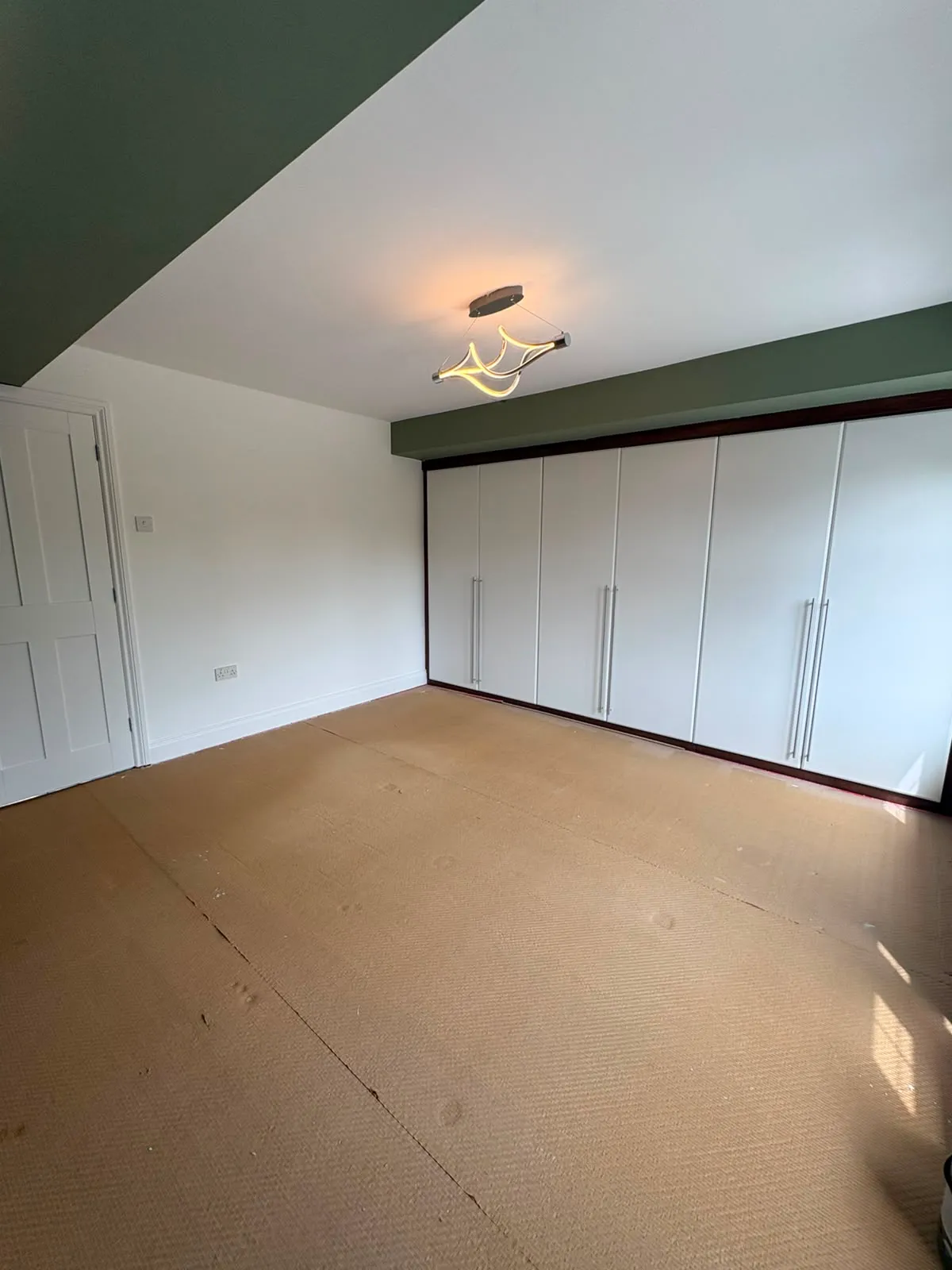The same bedroom after, with the fitted wardrobes hand-painted white and the walls in green