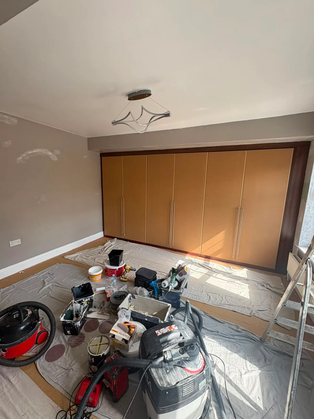 Bedroom before decorating, with beech fitted wardrobes and beige walls