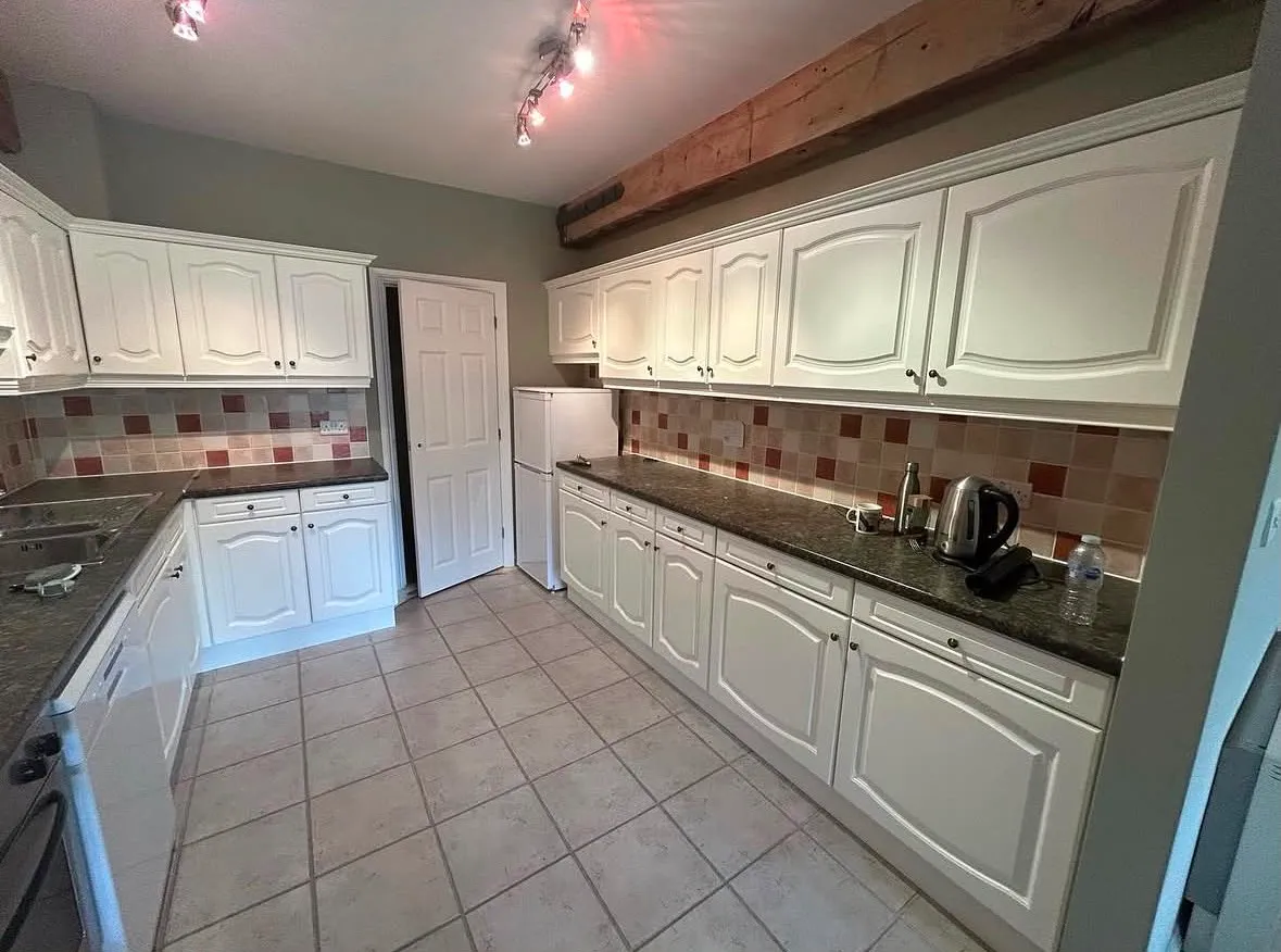 The same kitchen after, with the units sprayed white and the walls in sage green