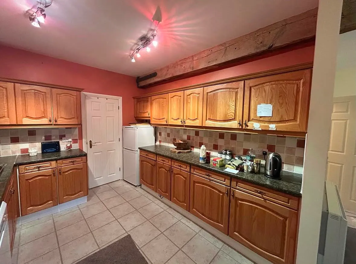 Kitchen before decorating, with orange oak units and red walls