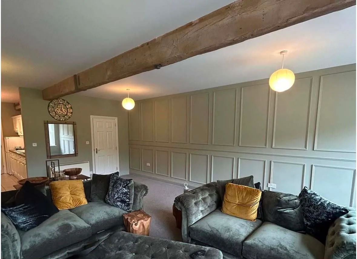 The same living room after, with full-height panelling painted sage green