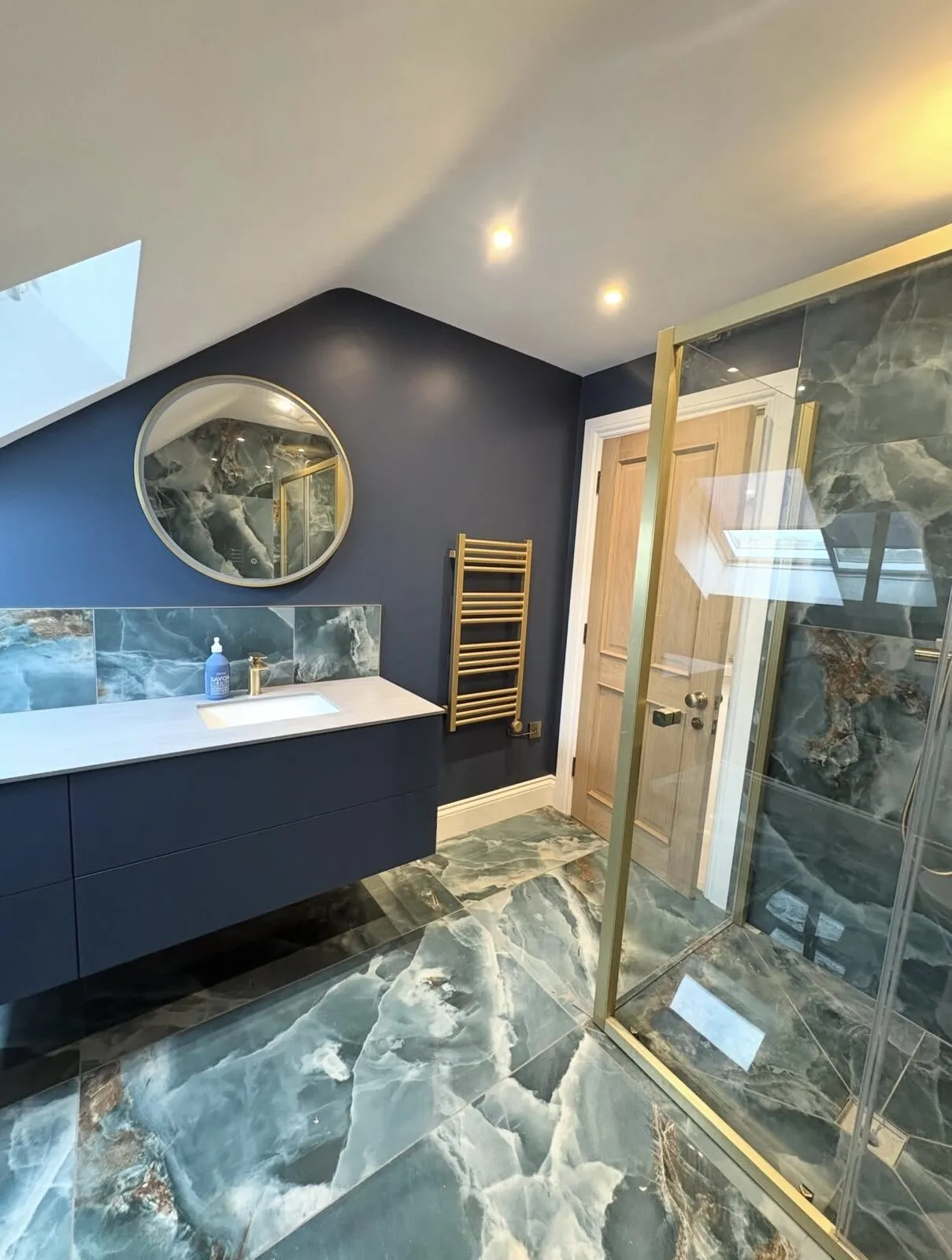 En-suite bathroom with navy walls, marble-effect tiling and brass fittings