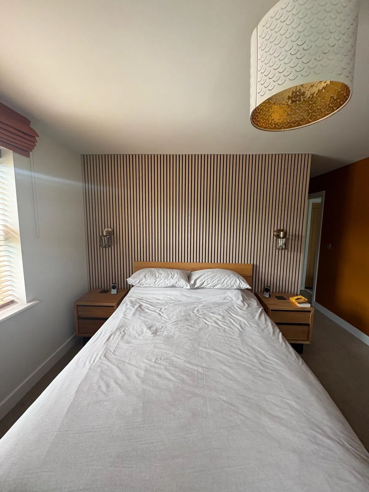 Bedroom with a full-height oak slat panelled wall behind the bed