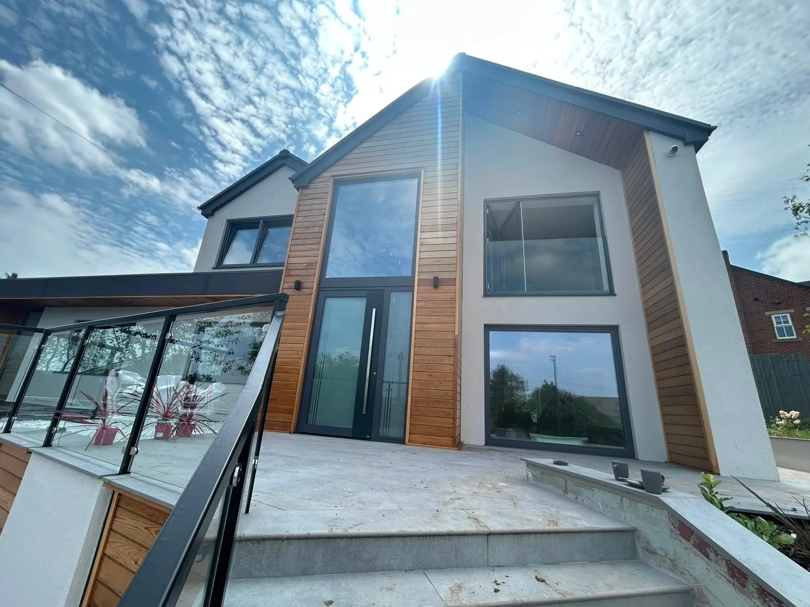 Modern rendered house with horizontal oak cladding around the front door and gable windows, sanded back and oiled