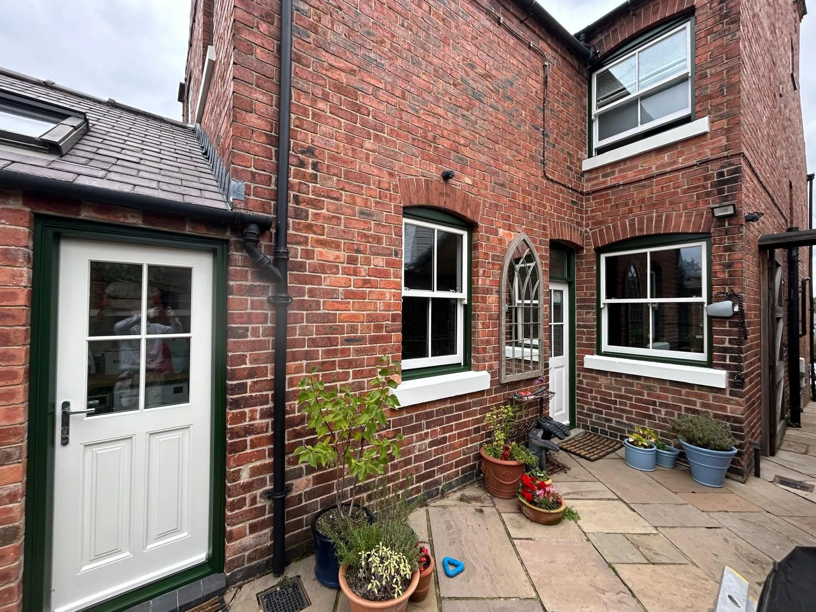 Rear elevation of a red brick house with timber joinery painted in green and white
