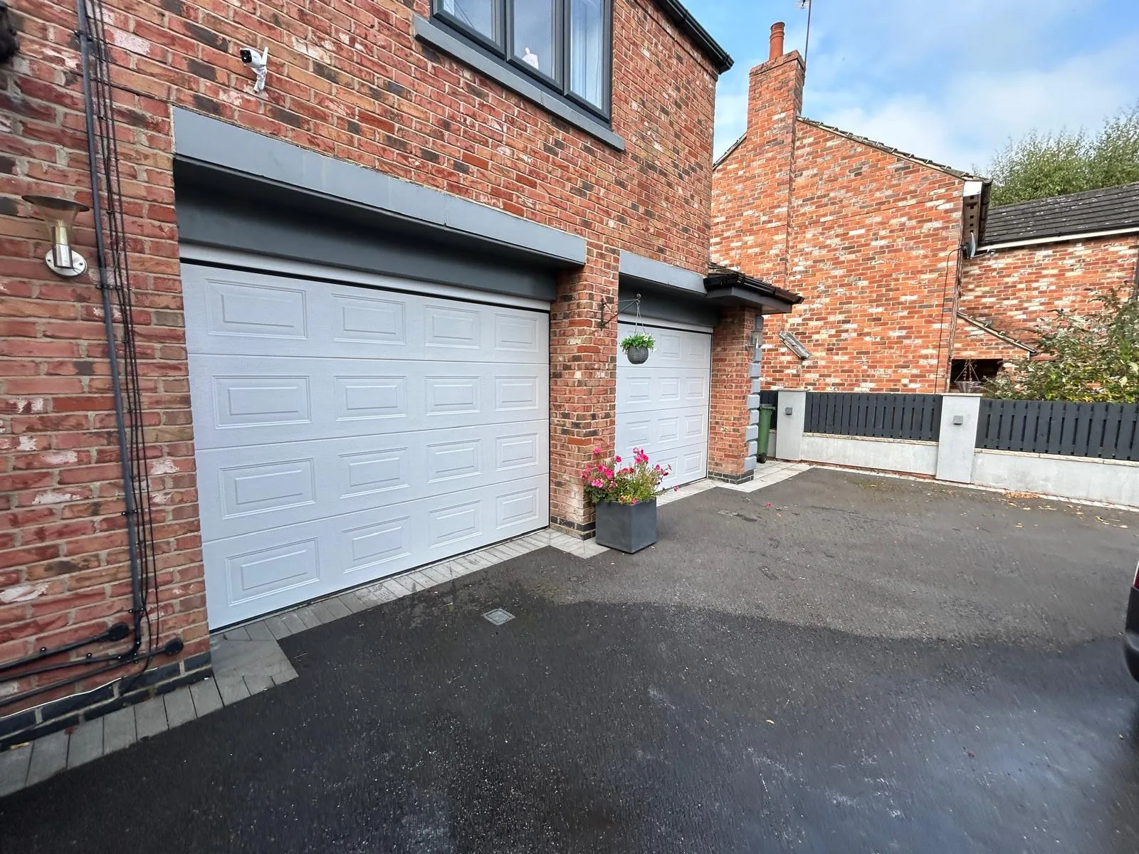 Two garage doors sprayed in white on a red brick house