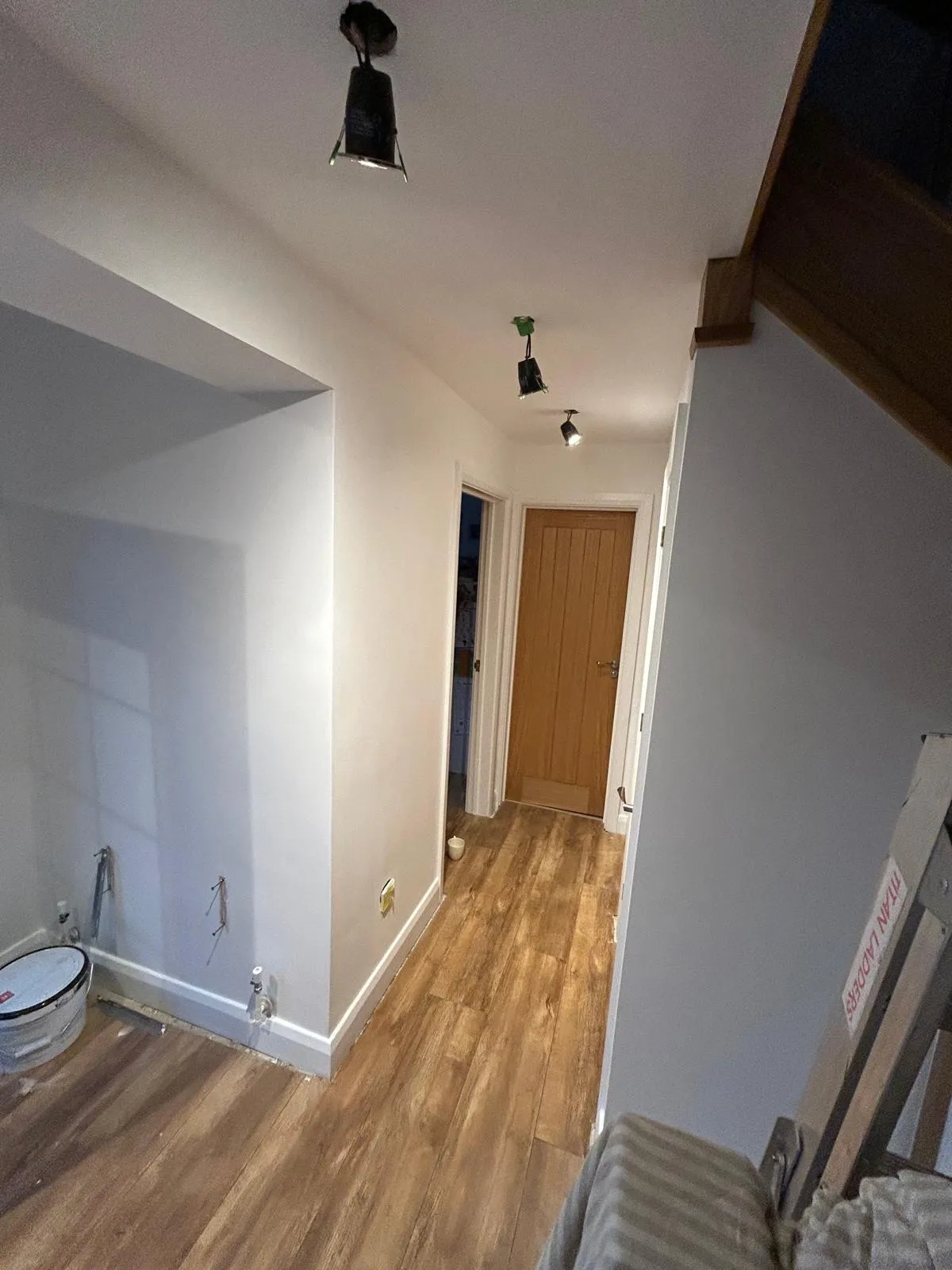 Finished hallway decorated in a soft white with an oak door and track spotlights