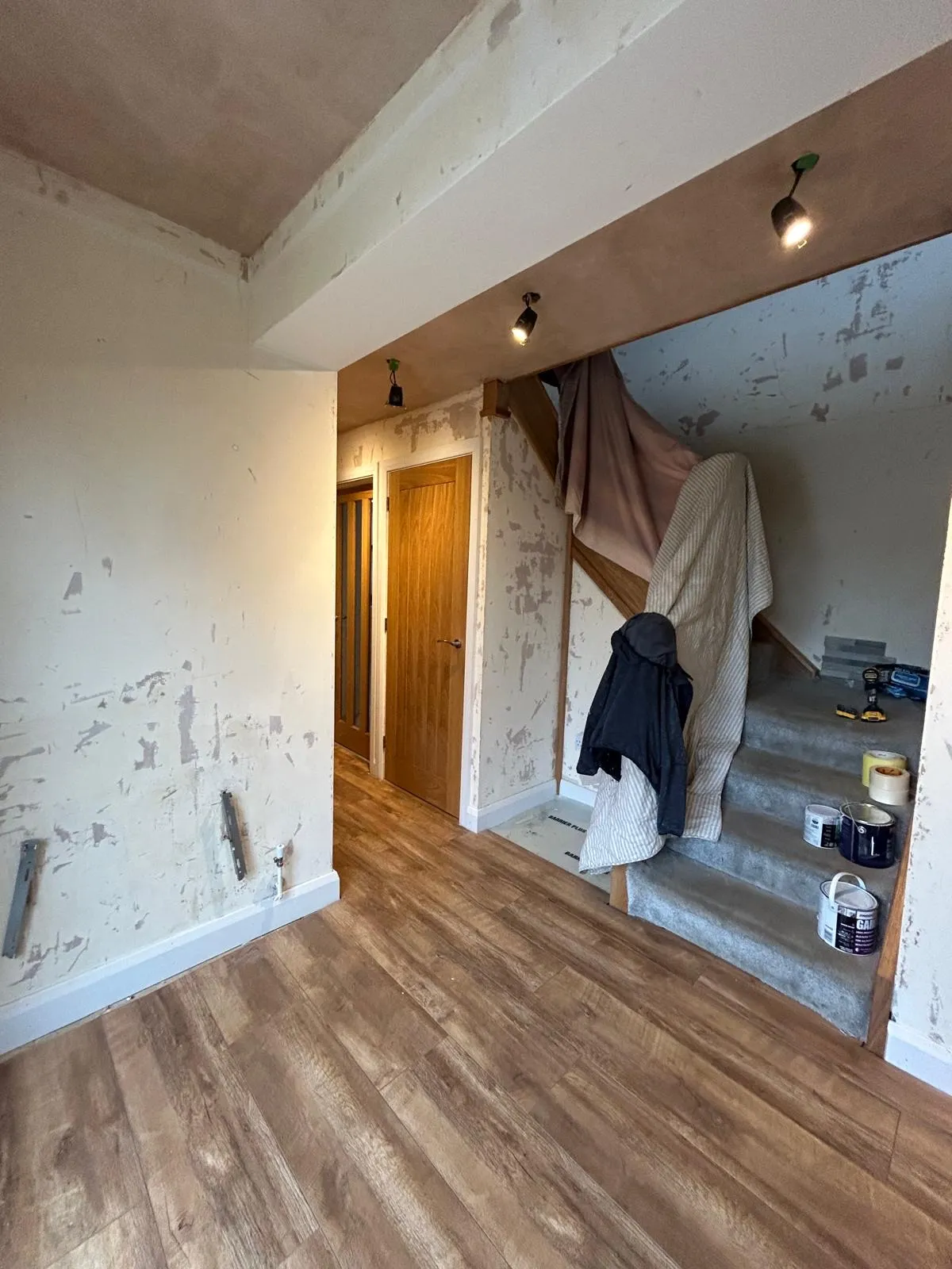 Hallway stripped back to bare plaster with the staircase uncovered