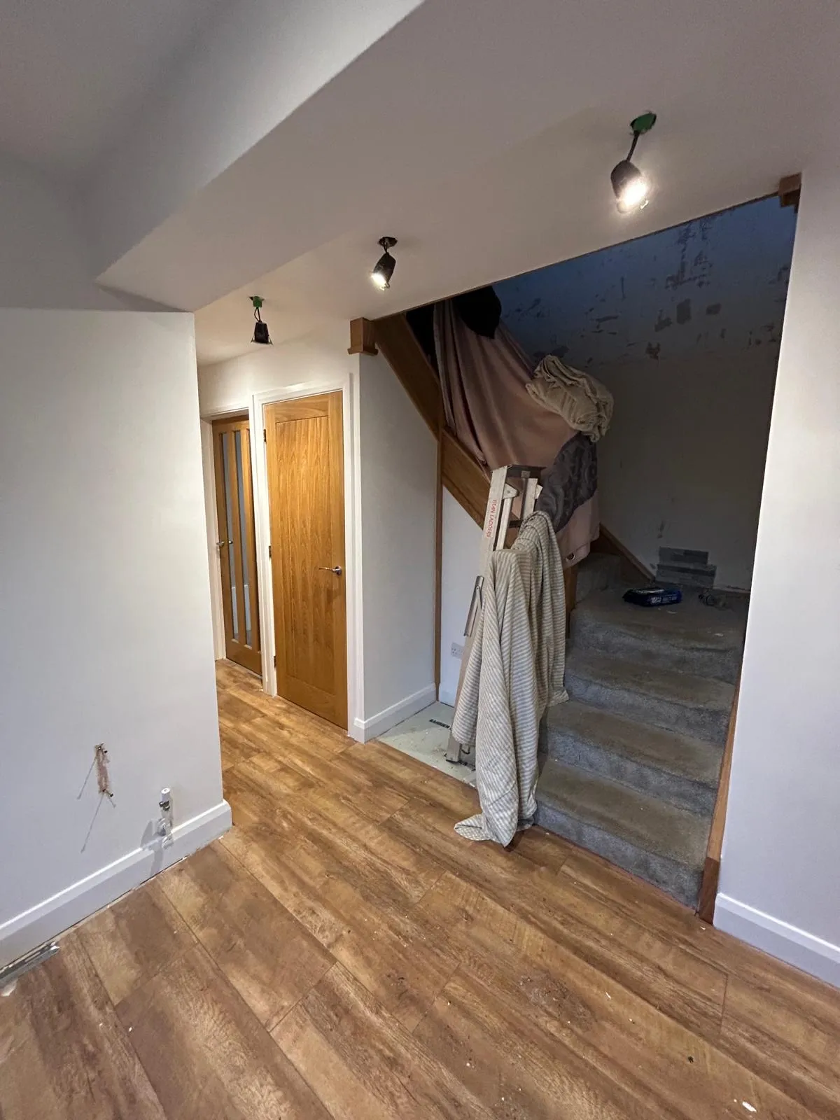 The same hallway part-way through, with the staircase sheeted and the new floor laid
