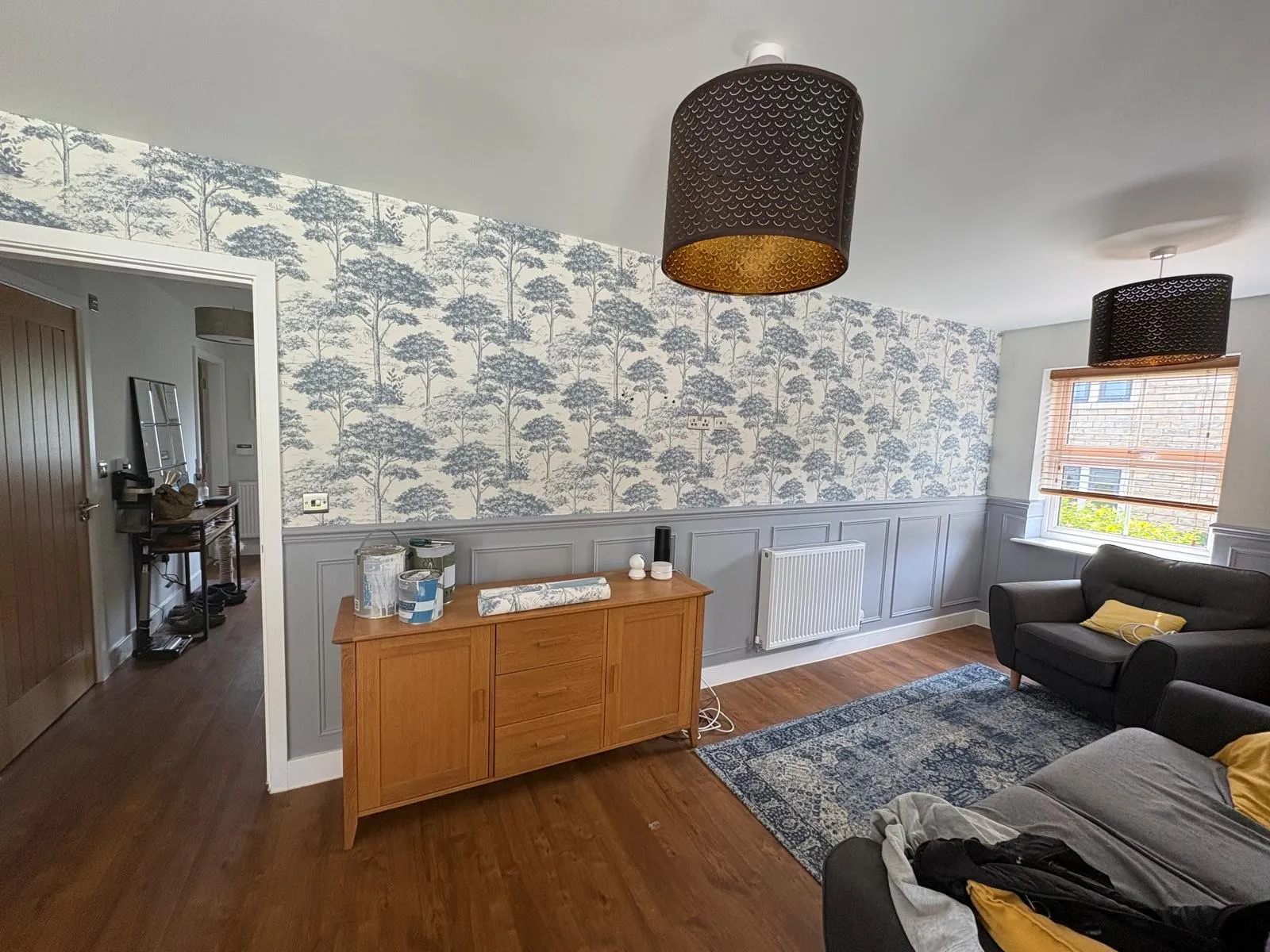 Living room with blue toile tree wallpaper above grey wall panelling