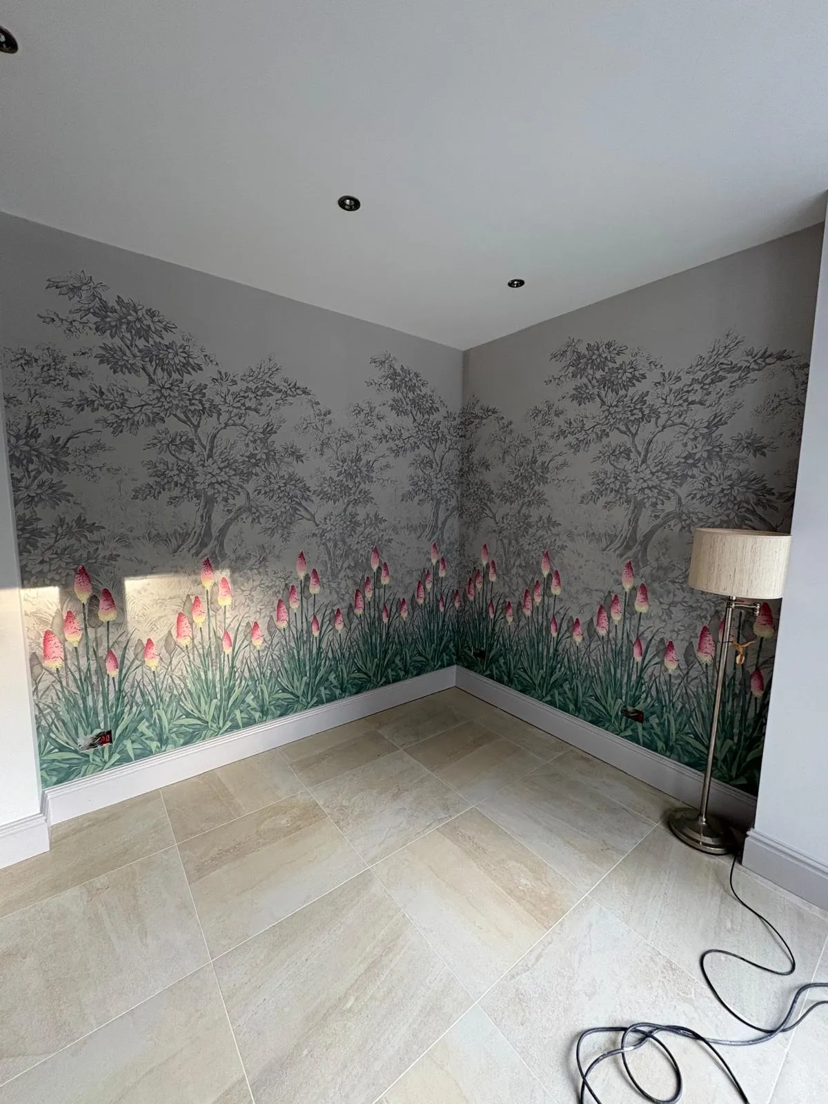 Living space with a hand-drawn tree and flower mural wallpaper across two walls