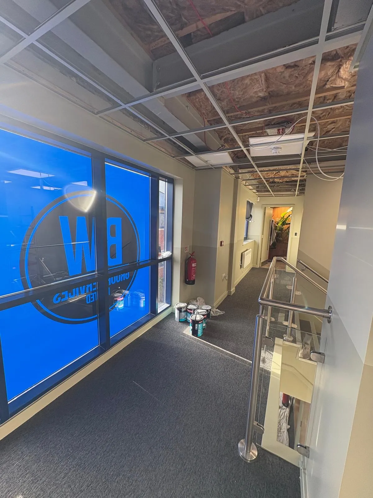 Office landing during refurbishment with the suspended ceiling grid stripped out and walls freshly cut in