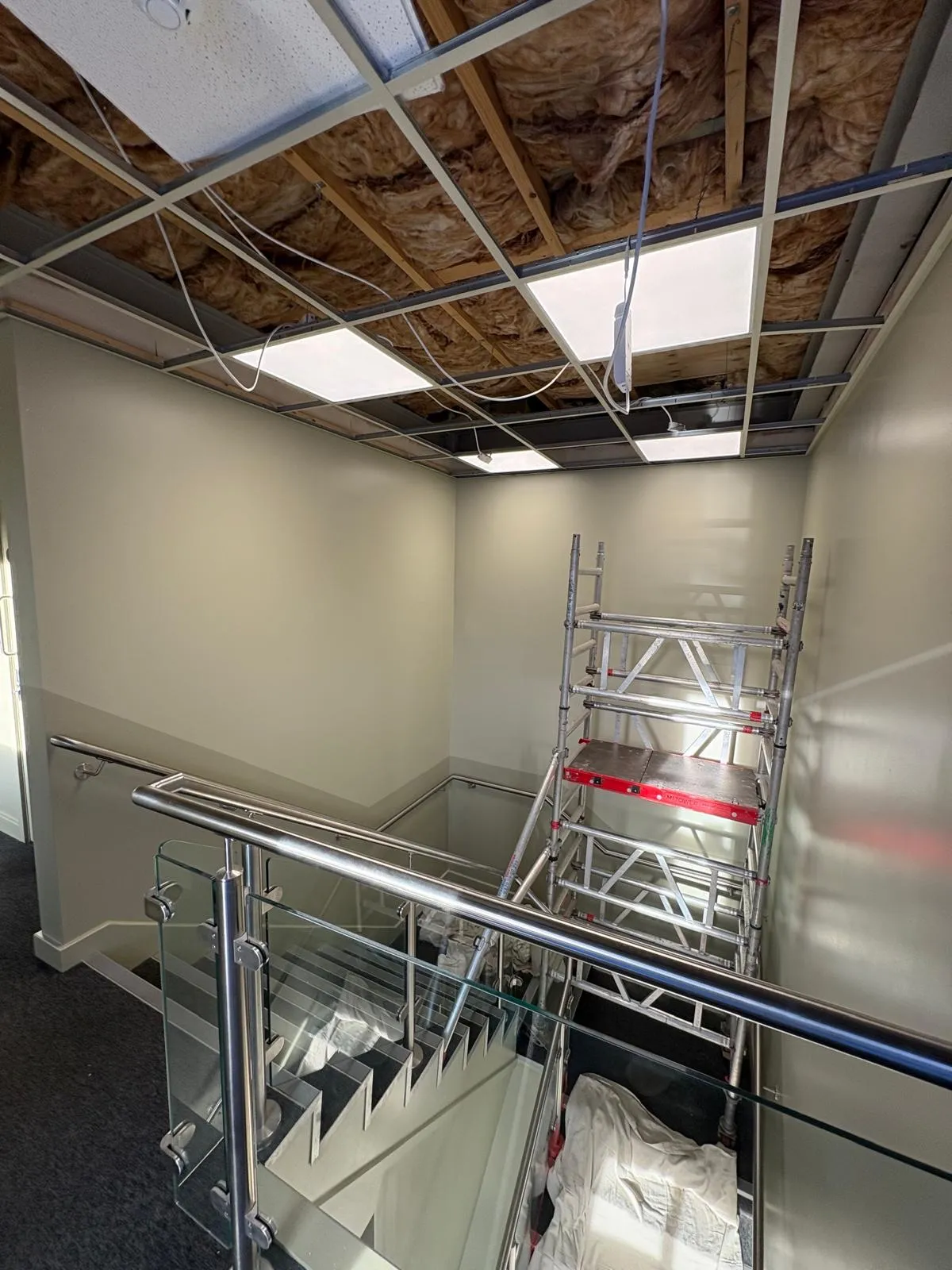 Commercial stairwell with a mobile scaffold tower up and the ceiling grid removed