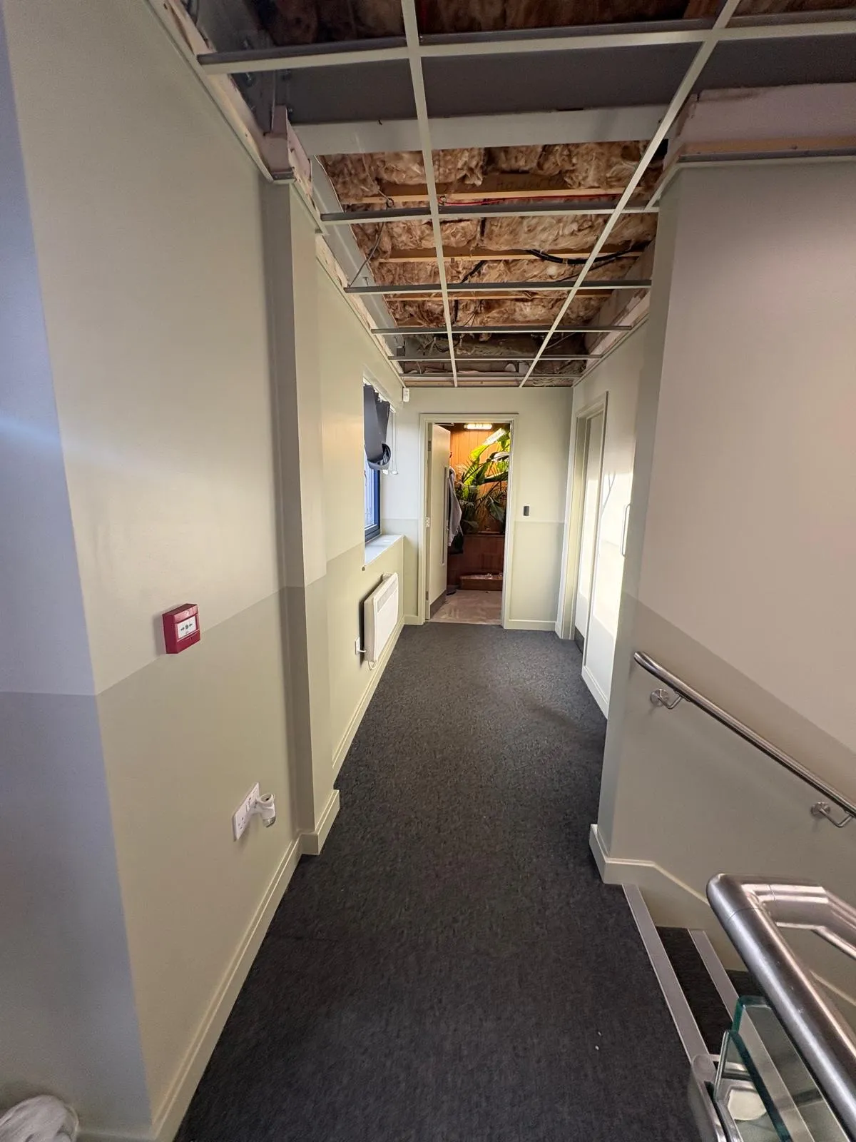 Office corridor freshly decorated in a soft neutral with the ceiling grid removed overhead