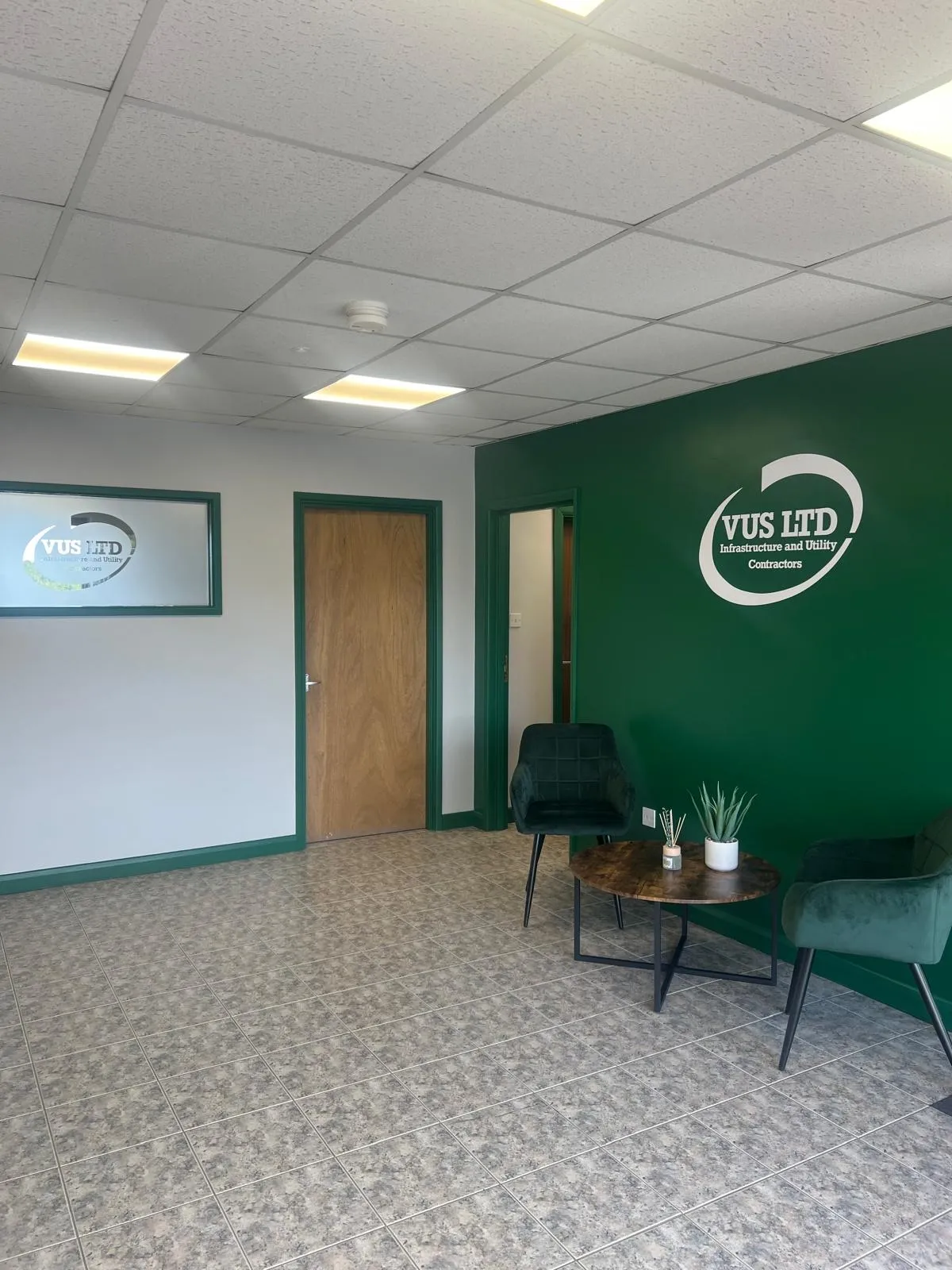 Office reception decorated with a deep green feature wall and white walls