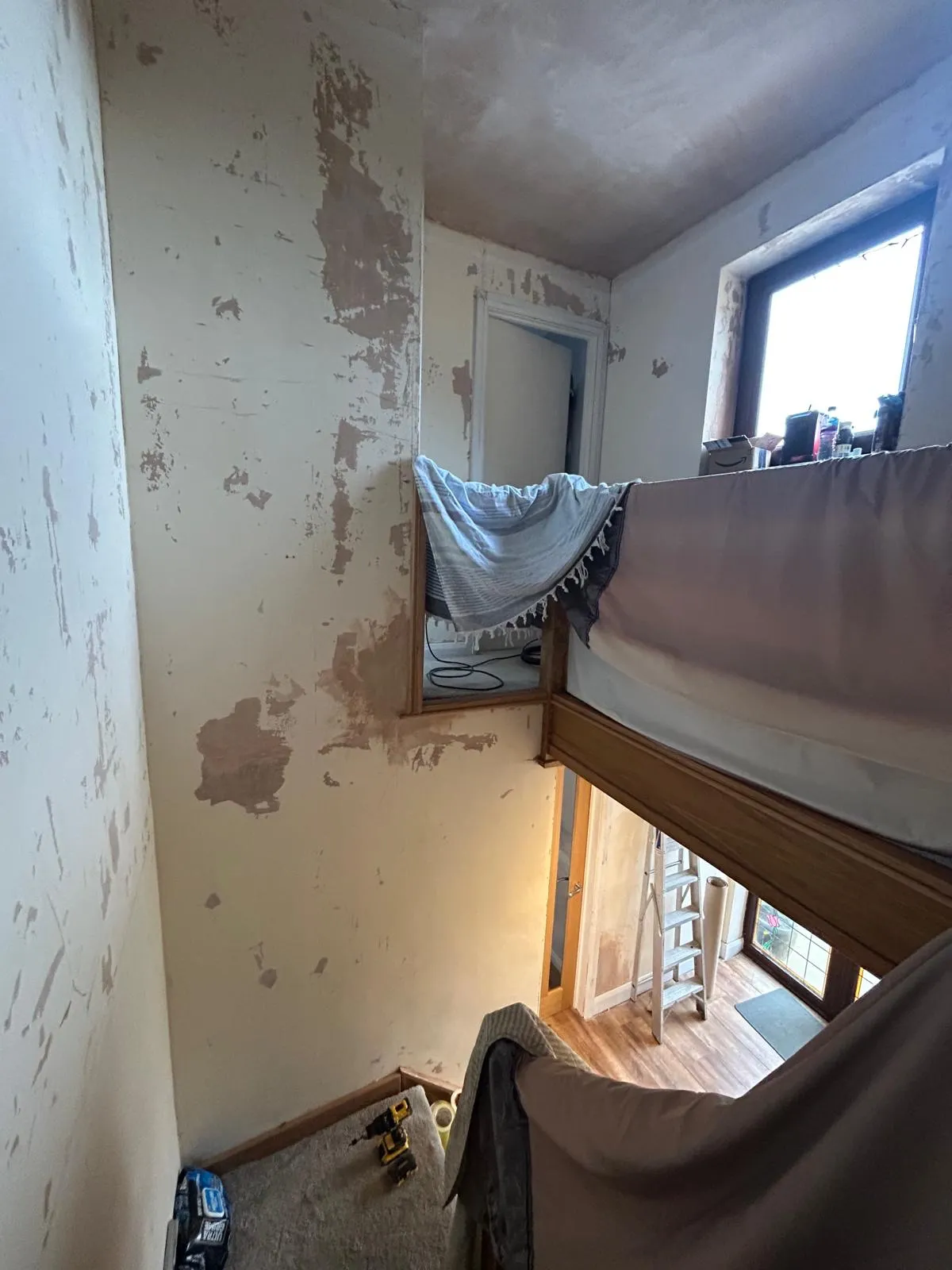 Stairwell wall stripped back to bare plaster with old paper removed