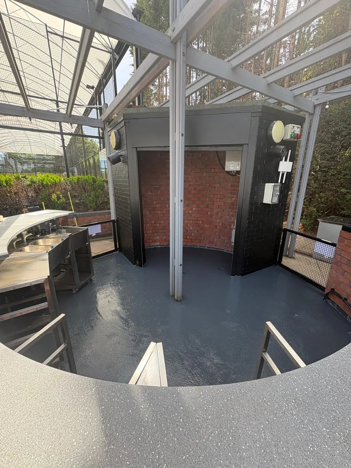Covered terrace at a health club with brickwork painted black and a grey painted floor