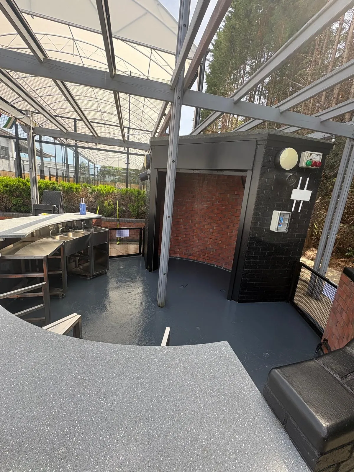 Covered outdoor terrace with black painted brickwork and a grey painted floor