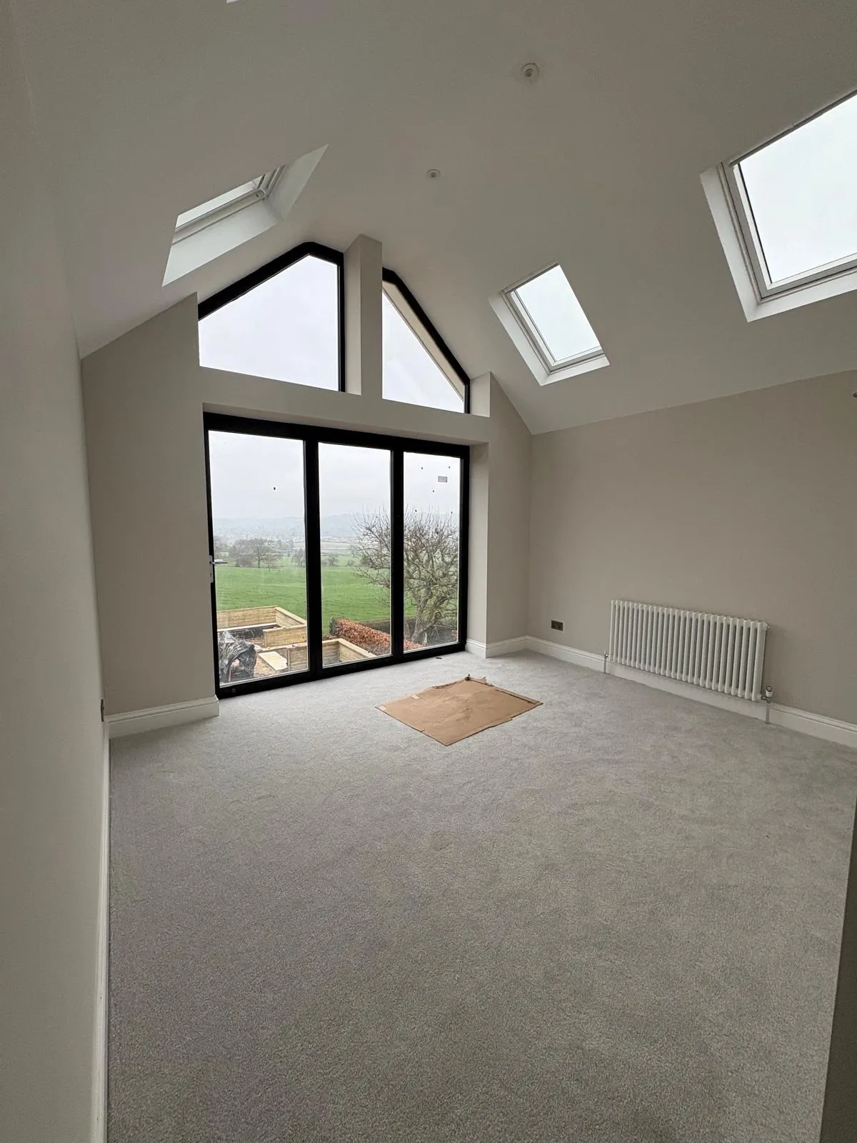 Vaulted new-build room with an apex window, roof lights and freshly decorated neutral walls